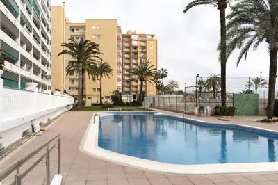 a swimming pool with palm trees and buildings at Lider, 2-I in Cullera