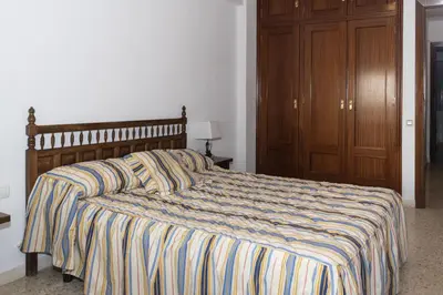 a bed with a striped comforter in a bedroom at Lider, 5-C in Cullera