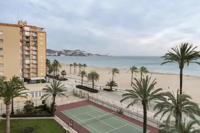 a tennis court with palm trees and a beach at Lider, 5-C in Cullera