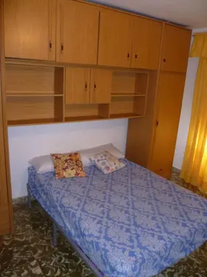 a small bedroom with a bed with wooden cabinets at Nautic, 7º-O in Cullera