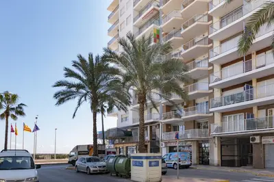 a building with palm trees in front of a parking lot at Nautilo, 8º-15 in Cullera