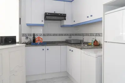 a white kitchen with white cabinets and blue accents at Saint Germain 7/B1, 8º-16 in Cullera