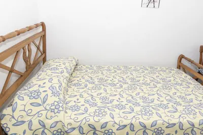 a bed with a blue and white blanket on it at Santa Marta, I-A 7º-19 in Cullera