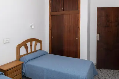 a bedroom with a blue bed and a wooden cabinet at Trianon, 5º-29 in Cullera