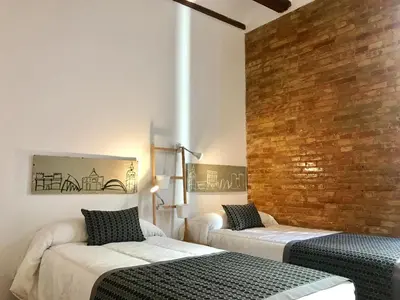 two beds in a room with a brick wall at Teixidors de Palomar - PalomarGroup in Valencia