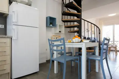 a kitchen with a white table and blue chairs at SingularStays Puzol Beach VI in Puzol