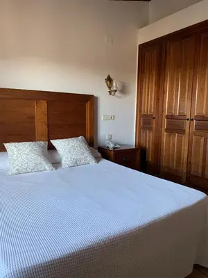 a bedroom with a large bed with a wooden headboard at Hotel La Villa in Requena