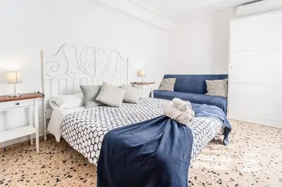 a bedroom with a white bed with a blue blanket at Casa Victoria in Valencia