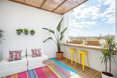 a balcony with yellow and white furniture and a window at Atico Valencia Sorolla in Valencia
