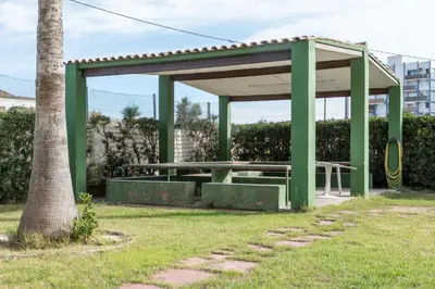 a green picnic shelter with a picnic table in a park at Apartamento Calipso in El Palmar