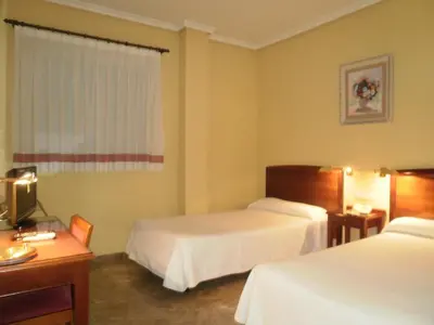 a hotel room with two beds and a desk at Hotel Isabel in Almussafes