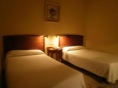 a hotel room with two beds and a night stand at Hotel Isabel in Almussafes