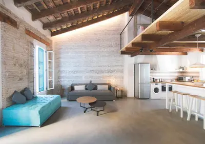 a living room with a blue couch and a kitchen at Apartamentos La más Bonita in Valencia