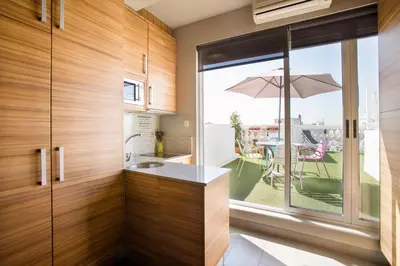 a kitchen with wooden cabinets and a patio with an umbrella at Sky Touristic Attic in Valencia