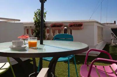 a table with a cup of orange juice and colorful chairs at Sky Touristic Attic in Valencia