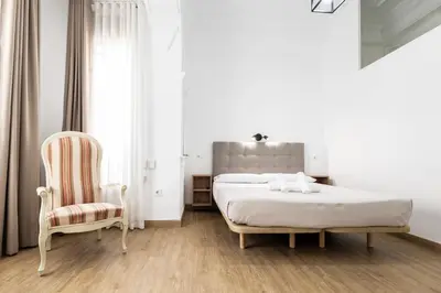 a white bedroom with a bed and a chair at Live in Chianti Apartaments by Concept Flats in Valencia