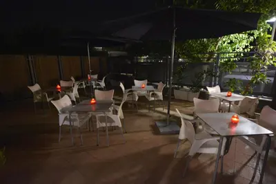 a patio with tables and chairs and an umbrella at Hotel Vista al Sol in Paterna