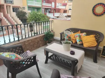 a patio with two chairs and a couch on a balcony at Dúplex, piscina y playa in Puebla de Farnals