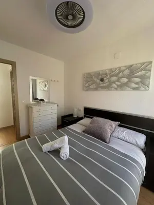 a bedroom with a large bed with two towels on it at Dúplex, piscina y playa in Puebla de Farnals