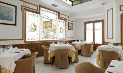 a restaurant with white tables and chairs and windows at Olympia Ronda Hostel in El Puig