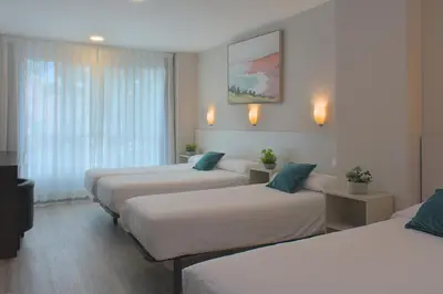 a hotel room with three beds and a window at Dormavalencia Hostel Regne in Valencia