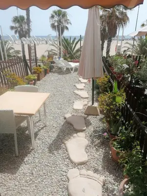 a patio with tables and chairs and an umbrella at Apartamento playa Las Arenas in Valencia