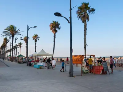 a group of people walking on a beach with palm trees at ApartUP Patacona Attic I in Valencia