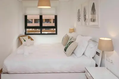 a white bedroom with a large white bed with pillows at ApartUP Patacona Attic I in Valencia