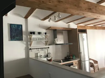 a kitchen with white walls and wooden ceilings at Casa La Abuela in Chulilla