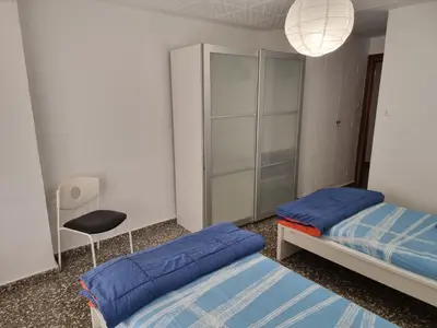 a bedroom with two beds and a chair and a lamp at Apartamento Ruzafa in Valencia