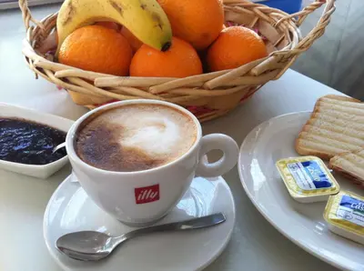 a cup of coffee on a plate with a basket of fruit at Hi Valencia Canovas in Valencia