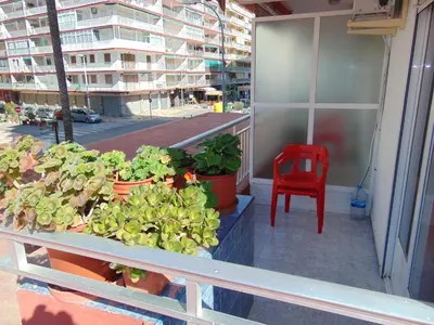 a red chair sitting on a balcony with plants at Hotel Libertador in Cullera