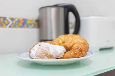 two croissants on a plate on a counter with a coffee pot at VLC - Cisneros in Valencia