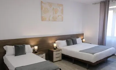 two beds in a hotel room with two lamps on them at Hostal Tartessos in Valencia