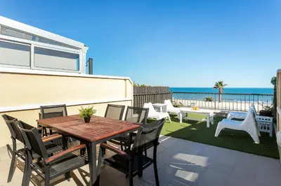 a patio with a wooden table and chairs and the ocean at ApartUP Patacona Terrace Duplex I in Valencia