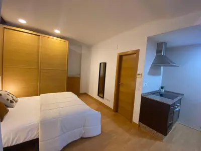 a bedroom with a white bed and a wooden door at Apartamentos La Xerea in Valencia