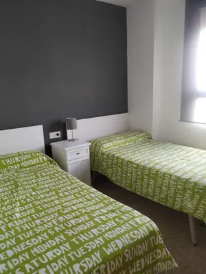 two beds in a room with green sheets and a nightstand at Apartamento Con Preciosas Vistas Al Mar,WIFI y piscina de temporada in Canet de Berenguer