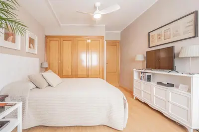 a bedroom with a white bed and a flat screen tv at 1ªLinea de playa Puerto de Sagunto in Puerto de Sagunto