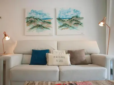 a white couch in a living room with paintings on the wall at ApartUP Patacona Beach II in Valencia