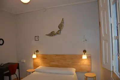 a bedroom with a bed with a wooden headboard and lights at Pensión Moratin in Valencia