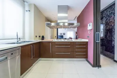 a kitchen with wooden cabinets and a pink wall at Travel Habitat Ático Ciutat Vella. in Valencia