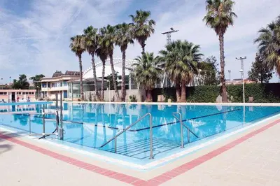 a large swimming pool with palm trees in the background at María montessori, pedagoga in Valencia