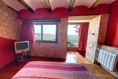a bedroom with red walls and a bed with a television at Casa Rural Mirador del Salto in Chella