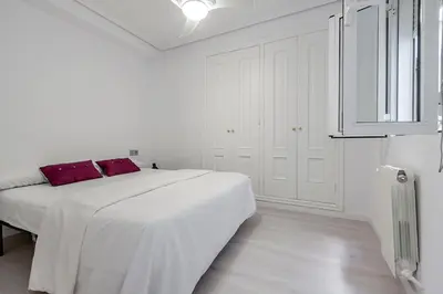 a white bedroom with a large white bed with red pillows at Carmen Apartment in Valencia