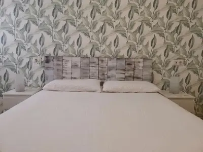 a bedroom with a white bed with a floral wallpaper at El apartamento de Marina en Moncofar playa in Moncófar