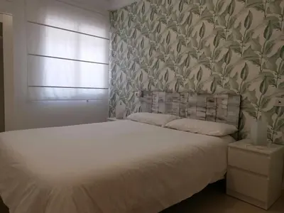 a bedroom with a white bed with a leafy wallpaper at El apartamento de Marina en Moncofar playa in Moncófar