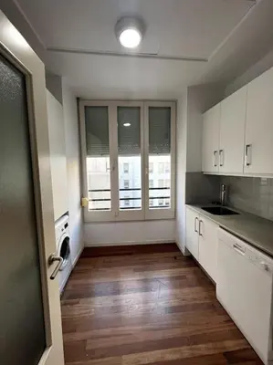a kitchen with white cabinets and a wooden floor at San Vicente in Valencia