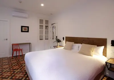 a large white bed in a room with a red chair at VALOLA Boutique Rooms in Valencia