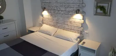 a bedroom with a bed with lights on a brick wall at Domus Valencia Apartamentos centro frente a Torres de Serrano in Valencia