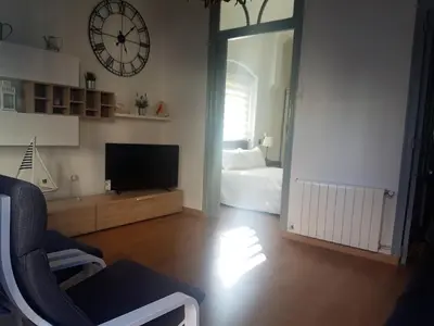 a living room with a bed and a clock on the wall at Apartamento con vistas a la Marina Real in Valencia